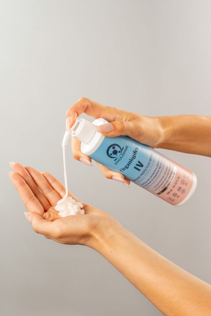 Main appliquant le masque Organiqplex avec un flacon pompe, gel blanc déposé dans la paume de la main