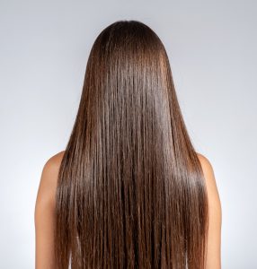 Femme aux cheveux longs, lisses et brillants après un soin capillaire réparateur