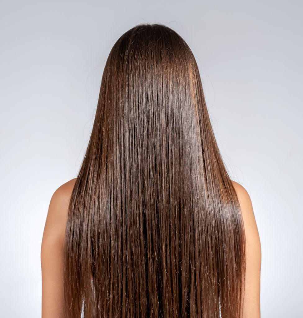 Femme aux cheveux longs, lisses et brillants après un soin capillaire réparateur