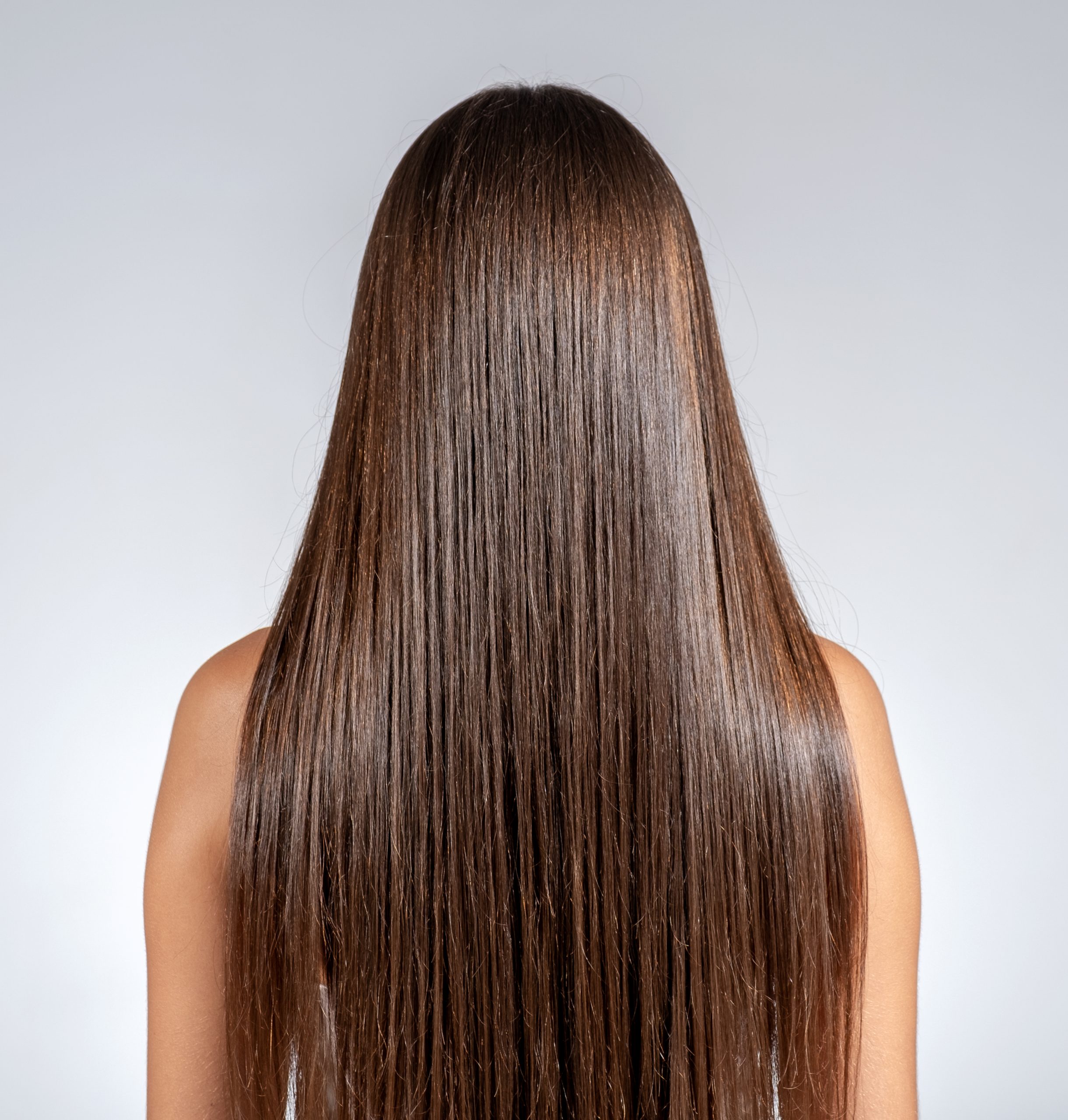 Femme aux cheveux longs, lisses et brillants après un soin capillaire réparateur